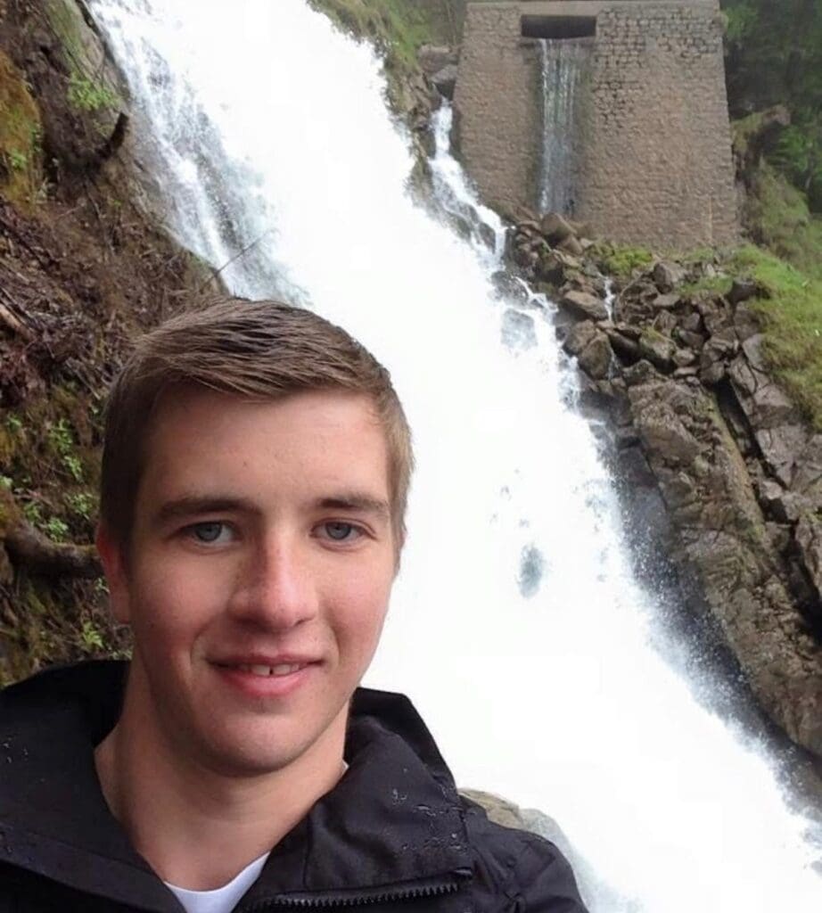 Sam when he was younger stood in front of a waterfall