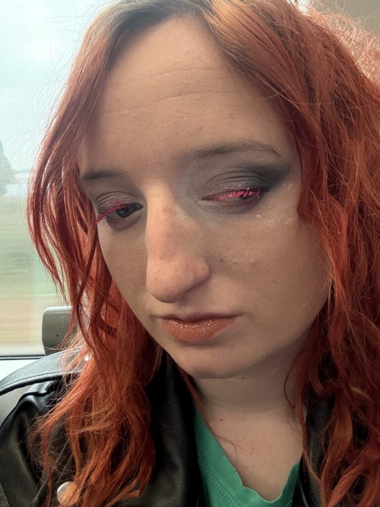 On the left: a selfie of Jerri Mather. She has light red wavy hair and smoky eyeshadow makeup with pink eyelashes. On the right: Jerri, wearing a red white and blue squiggly patterned Union Jack themed sports shirt plays a game of Showdown