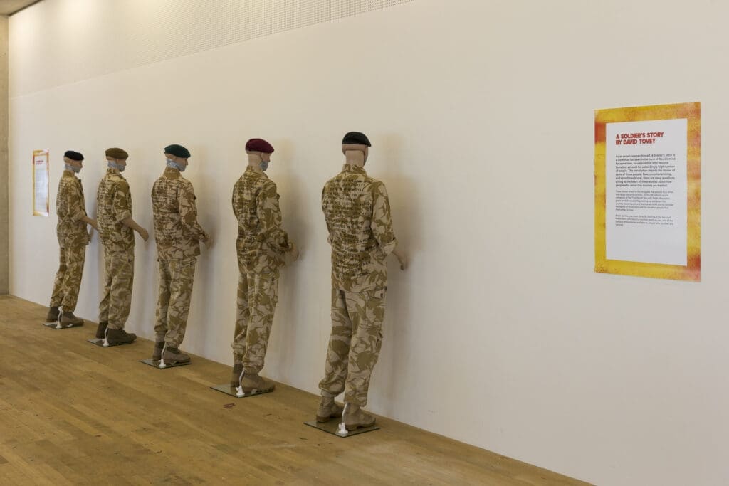Mannequins wearing Army uniform with case studies stitched on the back. 