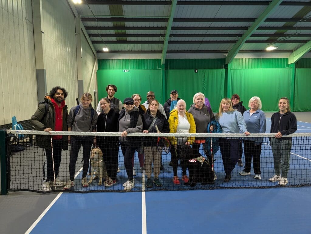 A group of members of SYVITC standing behind a tennis net 