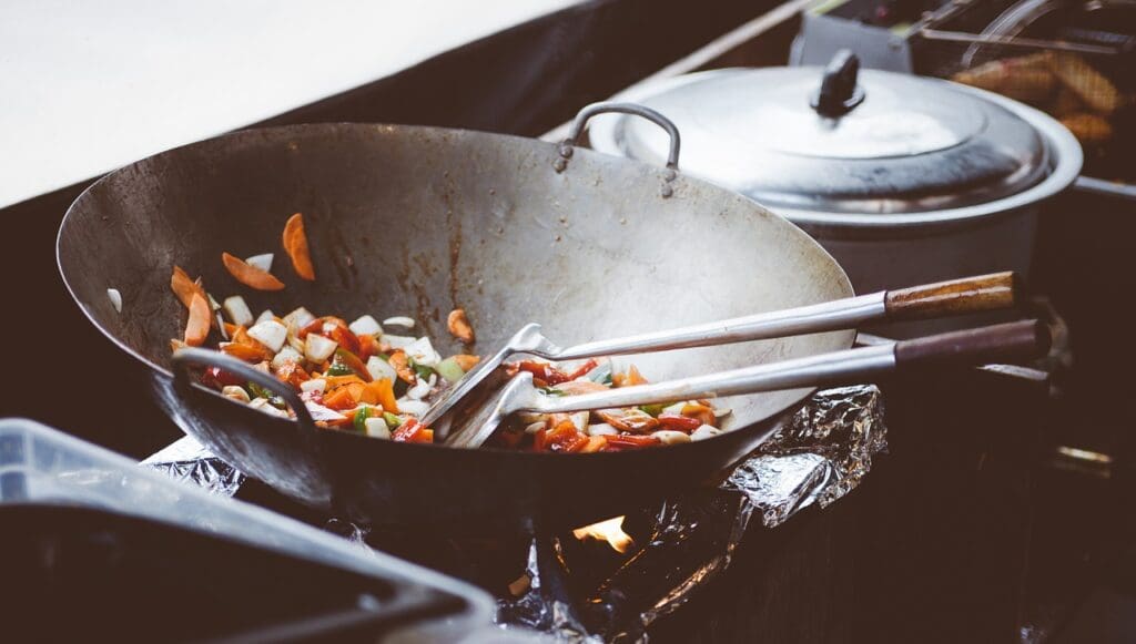 A wok with kitchen utensils on a stove