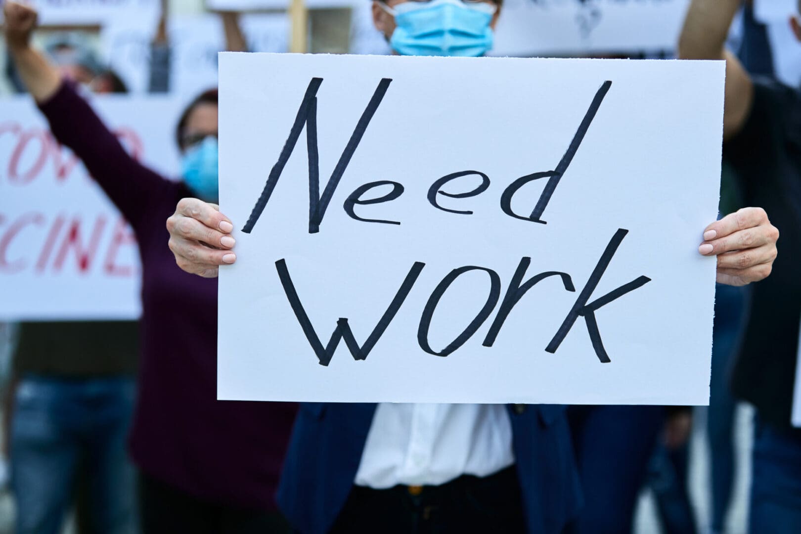Unrecognizable businesswoman protesting against unemployment holding banner with need work inscription