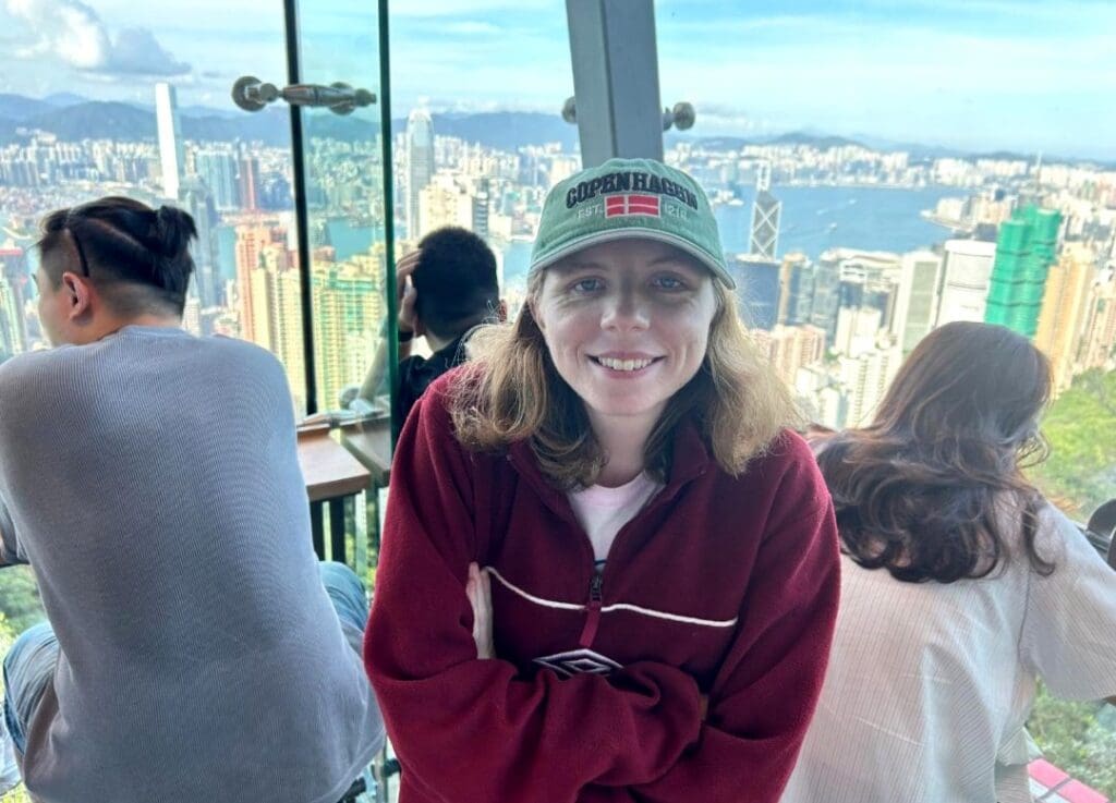 Kate taking a photo in front of the cityscape of Hong Kong.