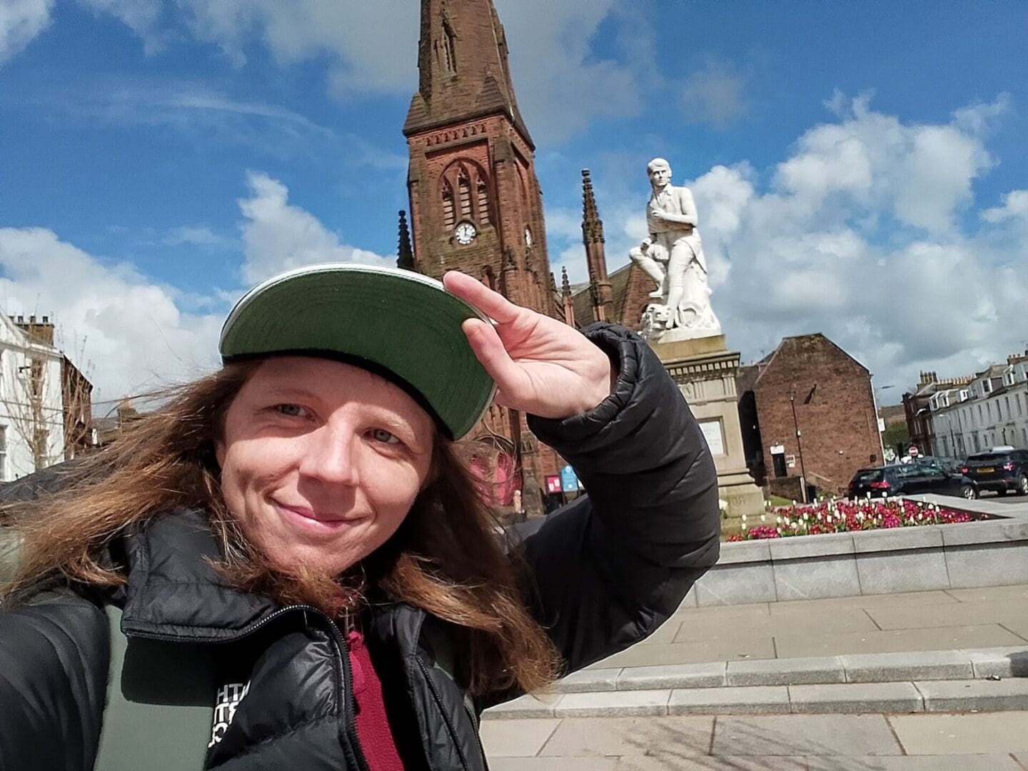 696679677_122230973678539783_3614333109080612461_n Kate smiles in front of a monument at Dumfries with a green cap.