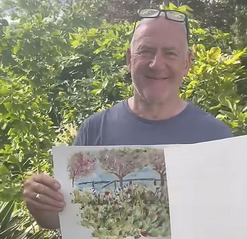 Screenshot A photo of Tim Hamilton in front of greenery in his garden holding one of his paintings of bushess and trees