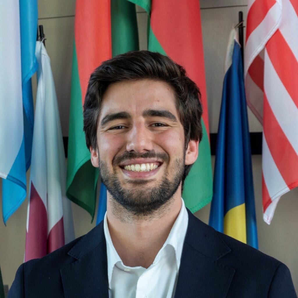 A photo of Andre Gomes smiling in front of several flags